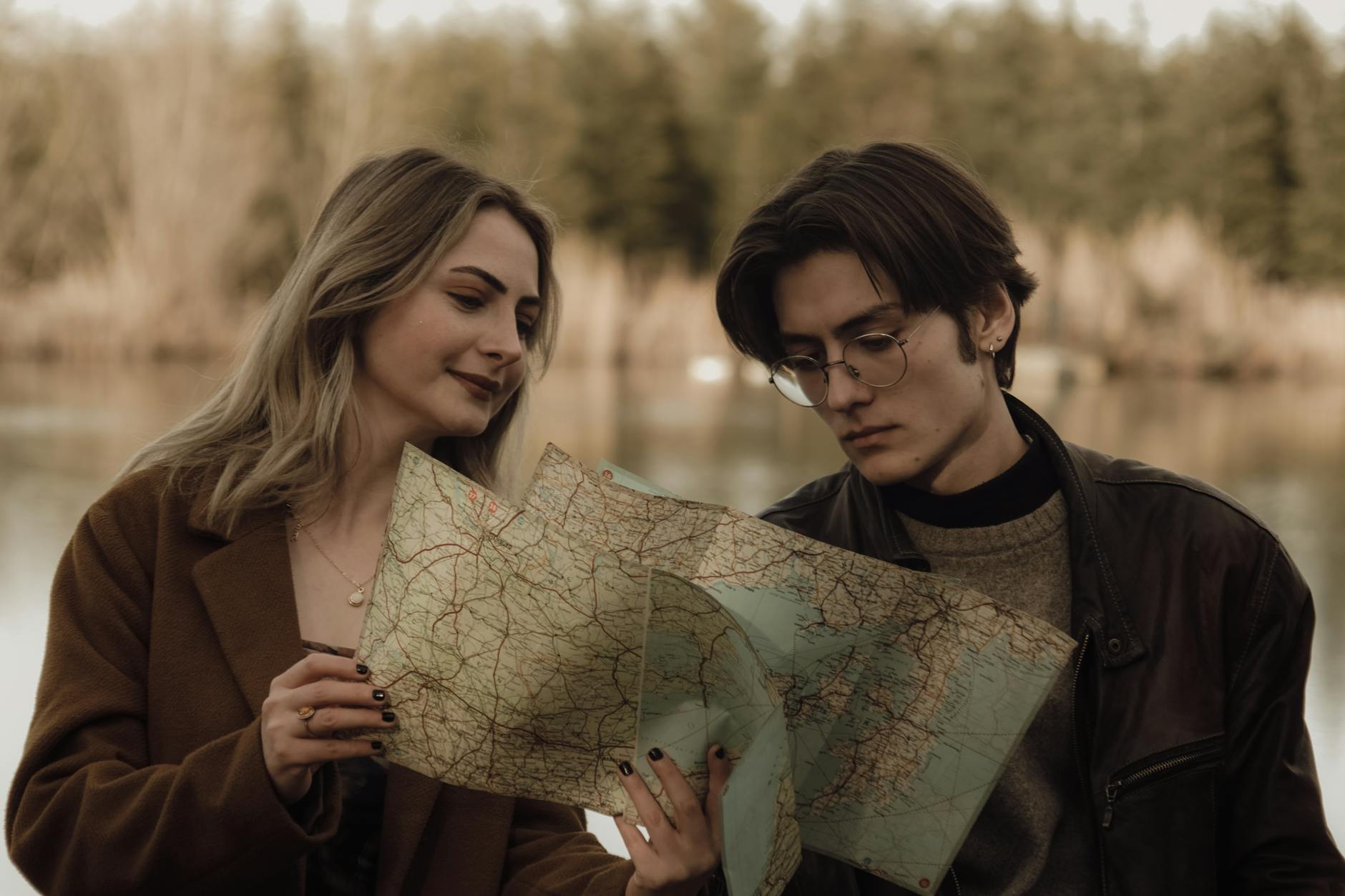 Młoda para nad jeziorem ogląda mapę i planuje wspólną podróż