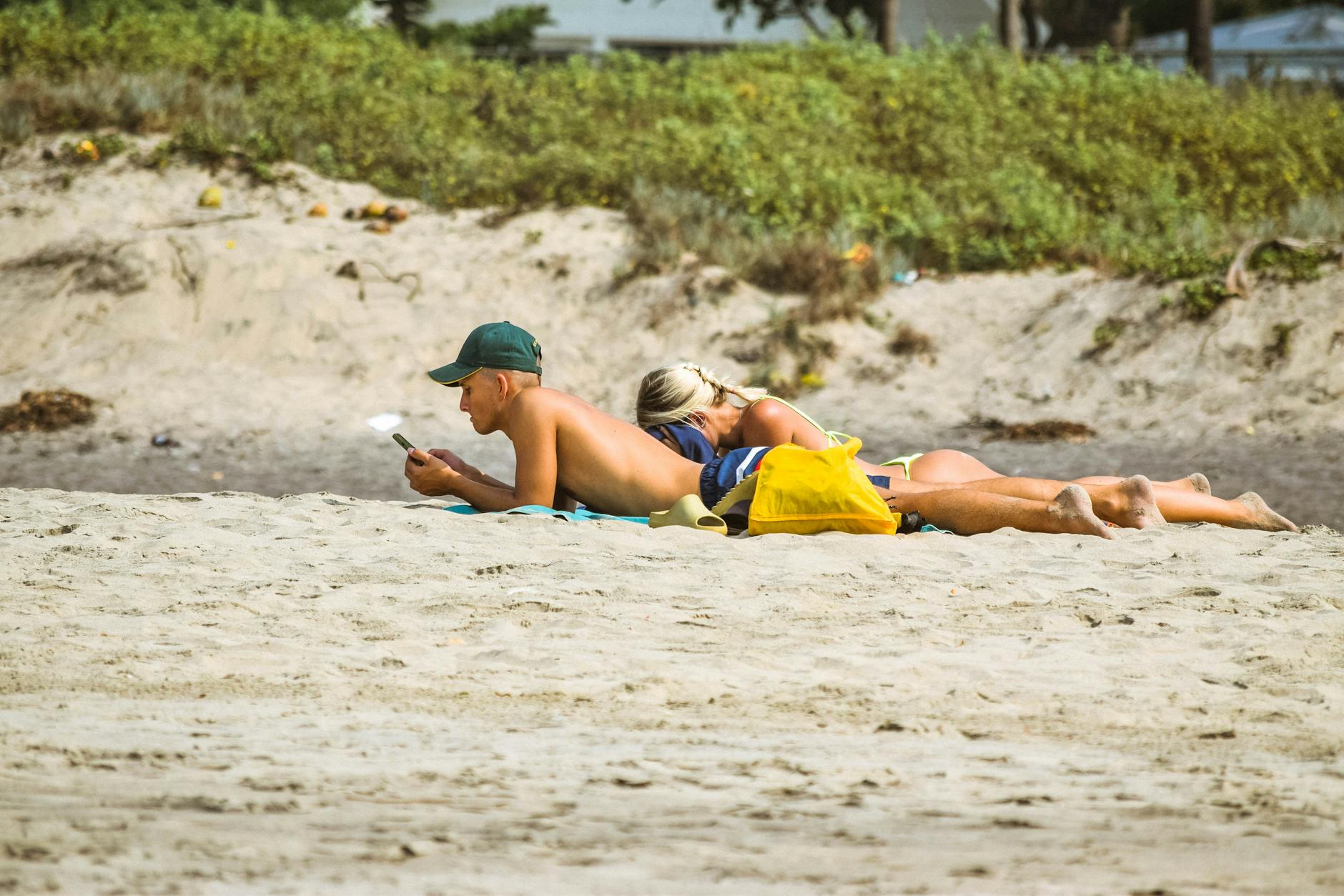 Opalanie w parze: jak okazywać czułość na plaży za granicą i nie robić sobie kłopotów Para opala się i czyta na słonecznej plaży Vagator w Goa