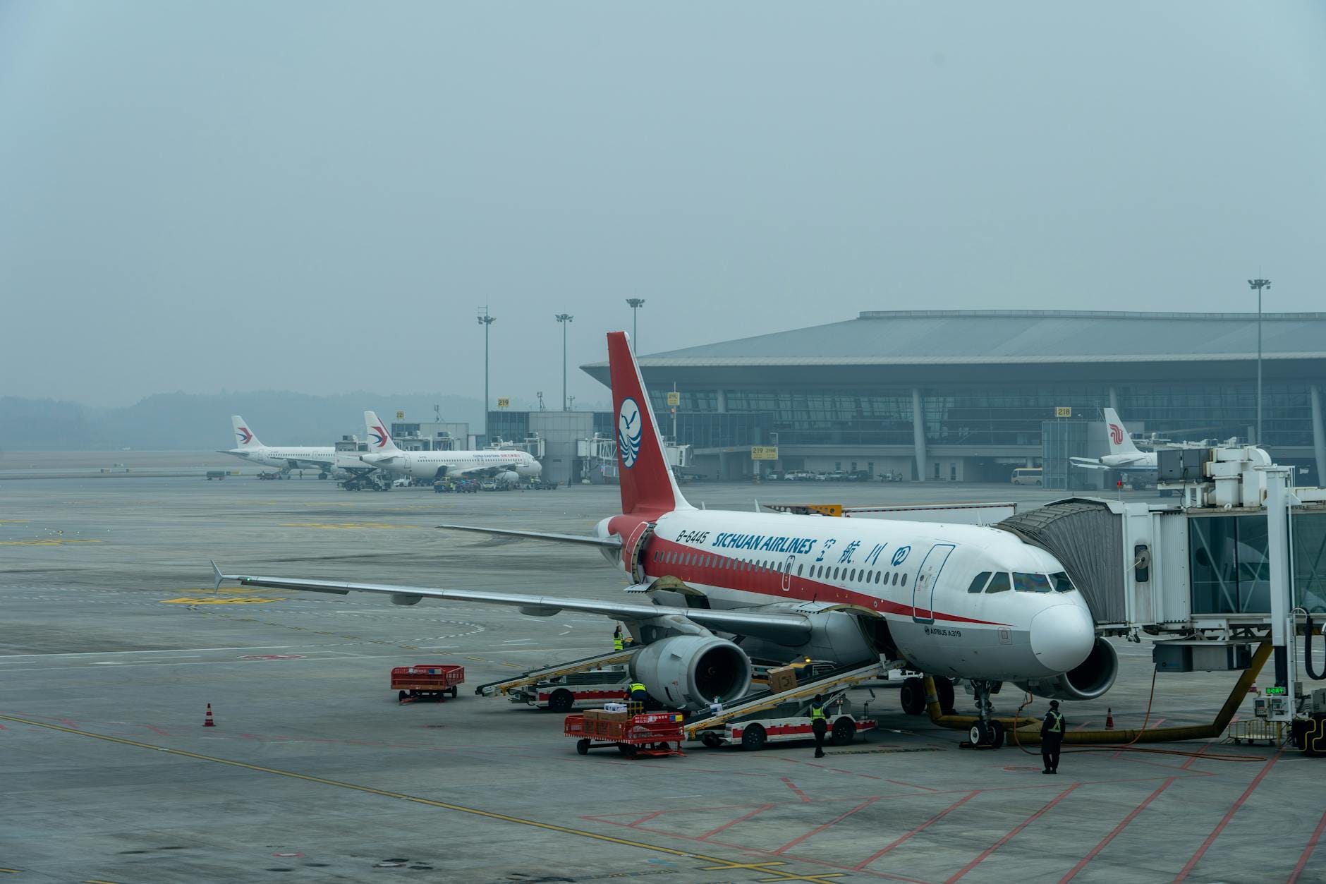 Samolot Sichuan Airlines Airbus A320 przy terminalu na zatłoczonym lotnisku