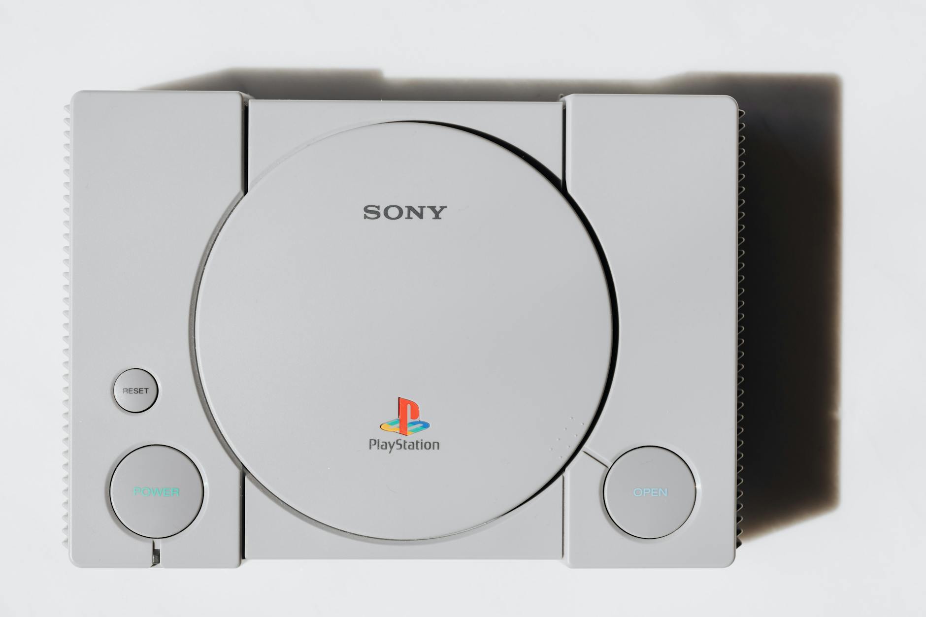 Od tekstowych przygodówek do fotorealizmu: jak zmieniały się gry komputerowe na przestrzeni dekad Zbliżenie klasycznej konsoli Sony PlayStation na białym tle