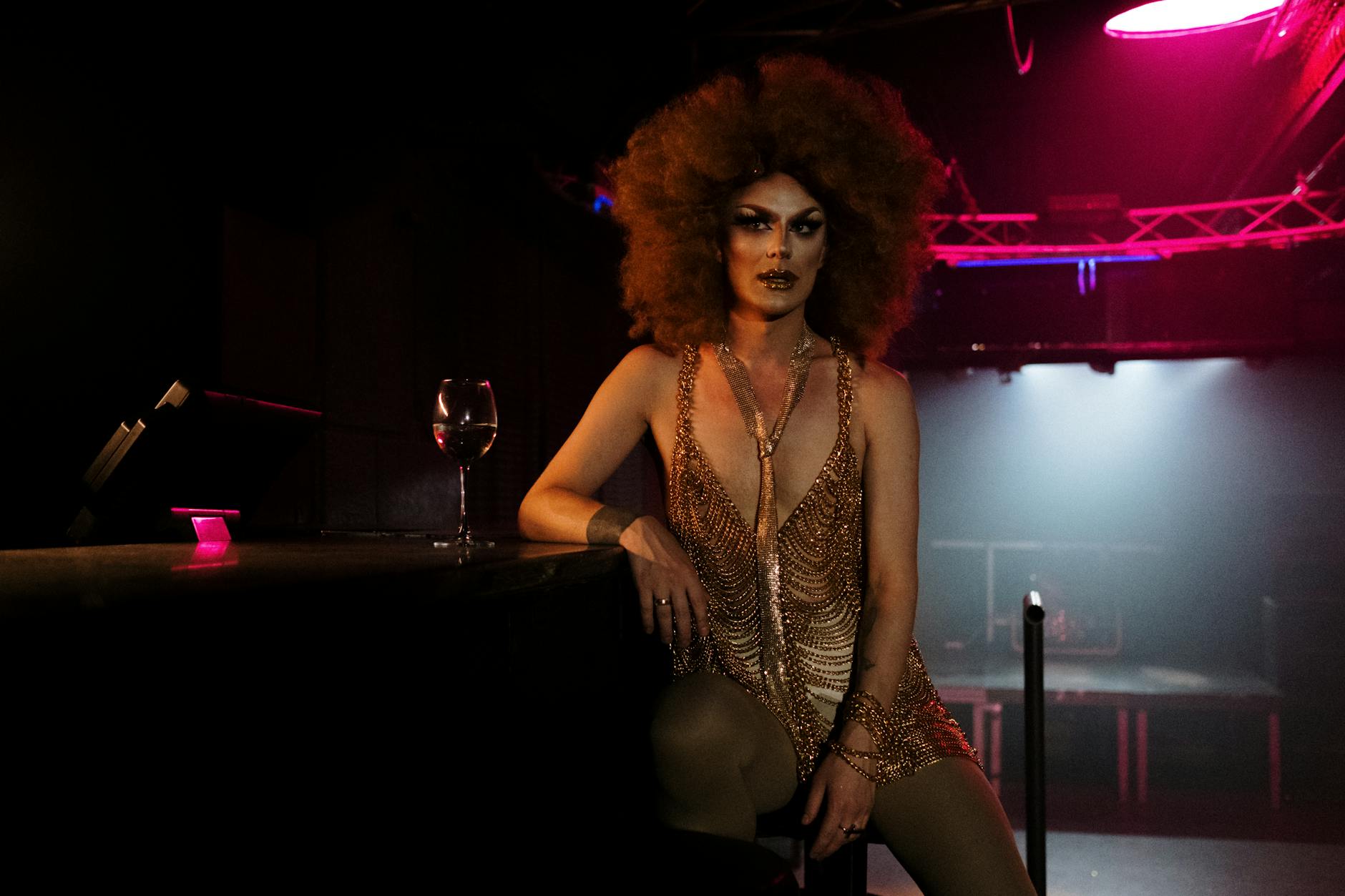 Drag queen z afro pozuje pewnie w kolorowym polskim klubie nocnym