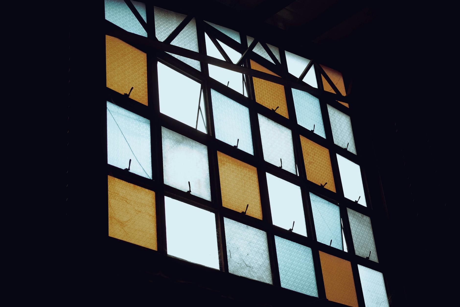 Podświetlone geometryczne witraże w ciepłych barwach w przyciemnionym wnętrzu