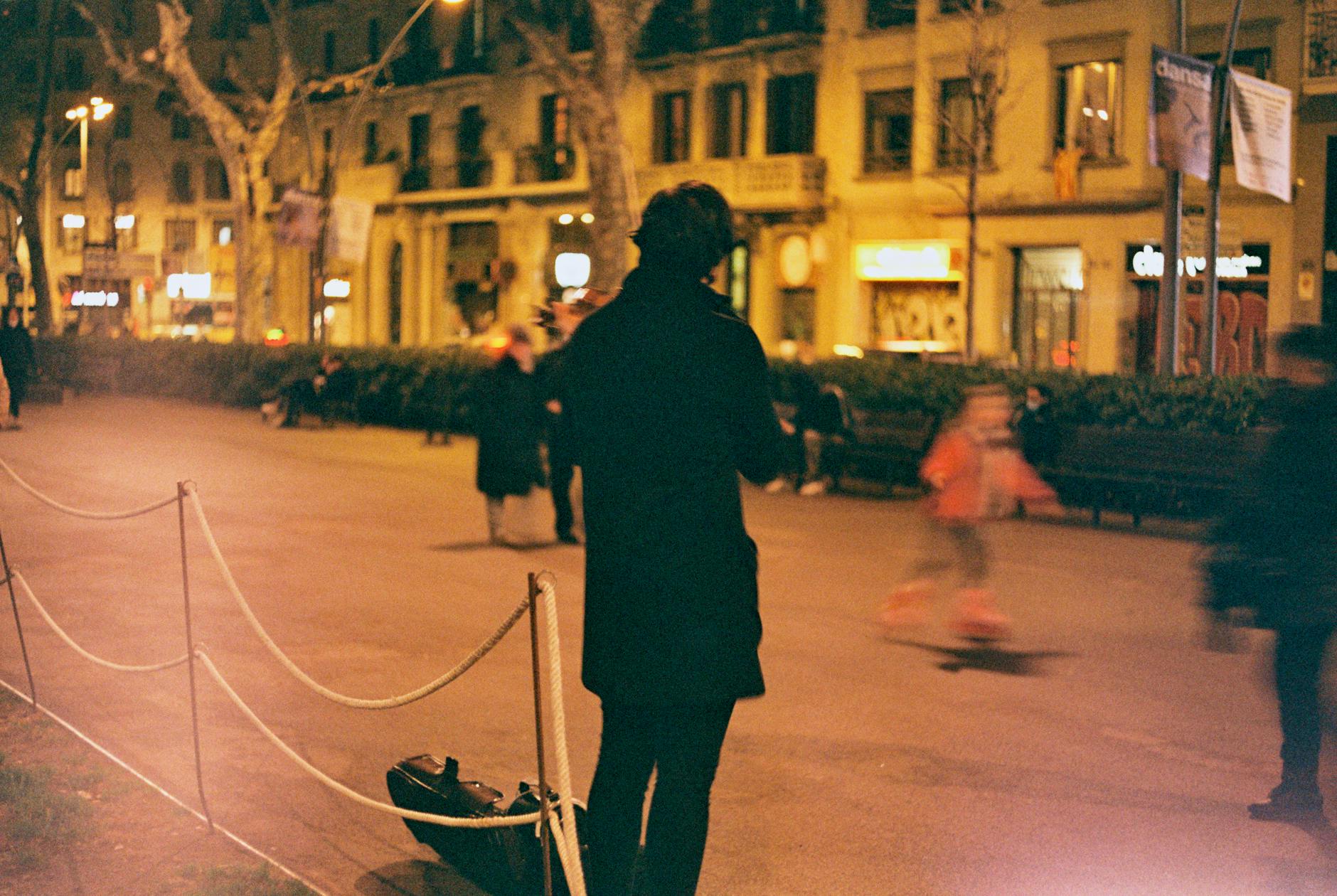 Skrzypek uliczny gra wieczorem na zatłoczonej ulicy w Barcelonie