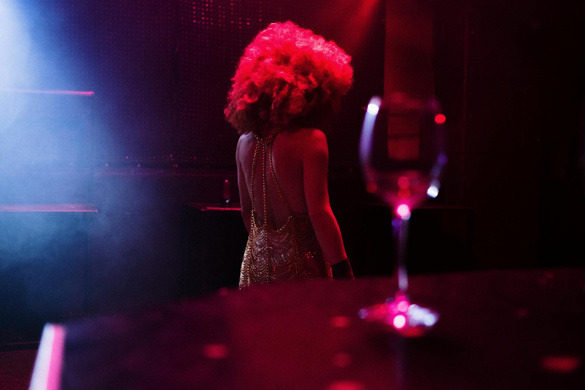 Drag queen na klubowej scenie w Wiedniu, kieliszek wina na pierwszym planie