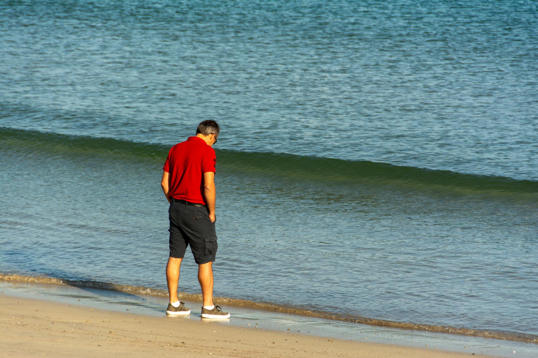 Mężczyzna spaceruje samotnie po spokojnej plaży na Cyprze