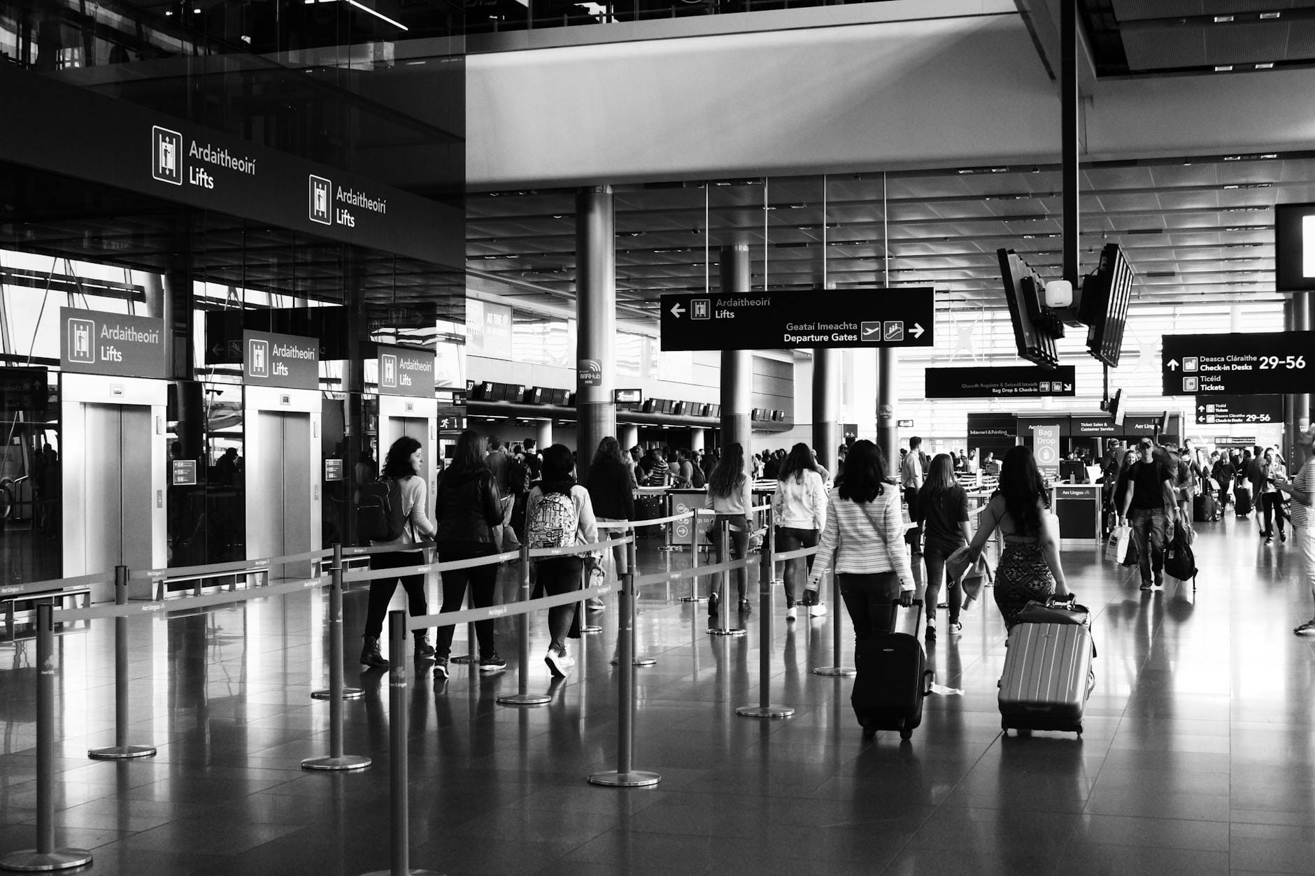 Pasażerowie z walizkami idą przez ruchliwy terminal lotniska