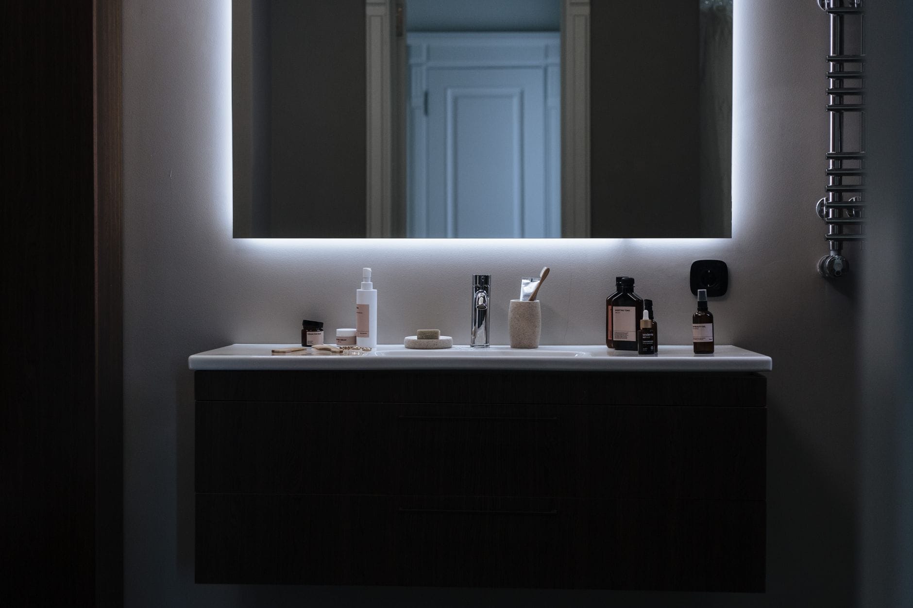 Minimalistyczna łazienka z lustr em LED i kosmetykami na blacie