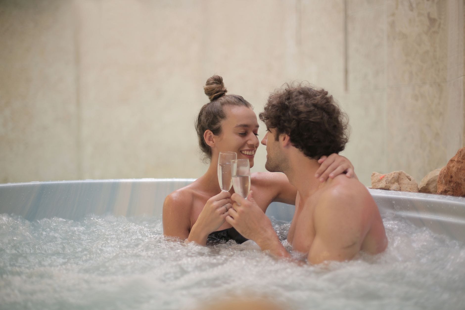 Para w jacuzzi z lampką szampana podczas romantycznego weekendu