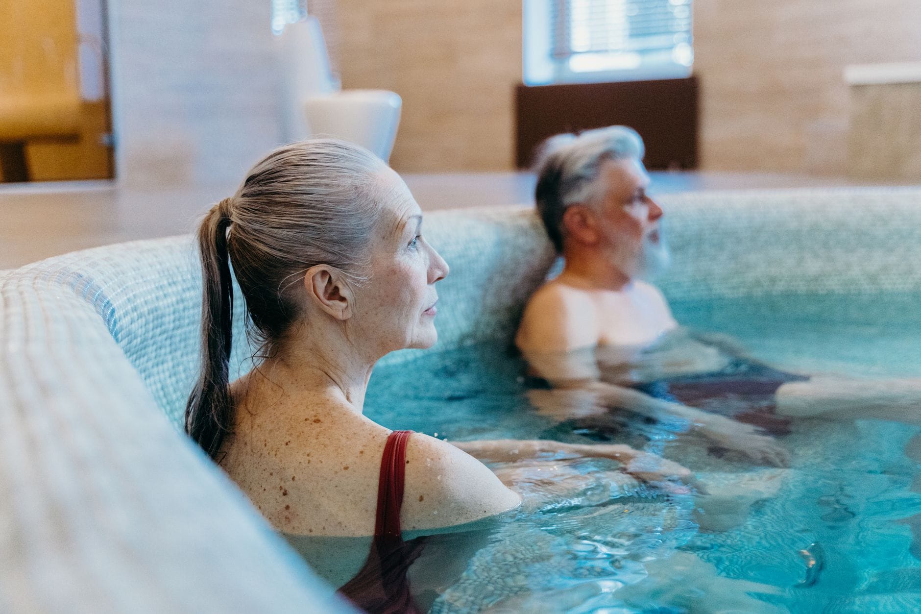 Starsza para relaksuje się razem w krytym basenie spa