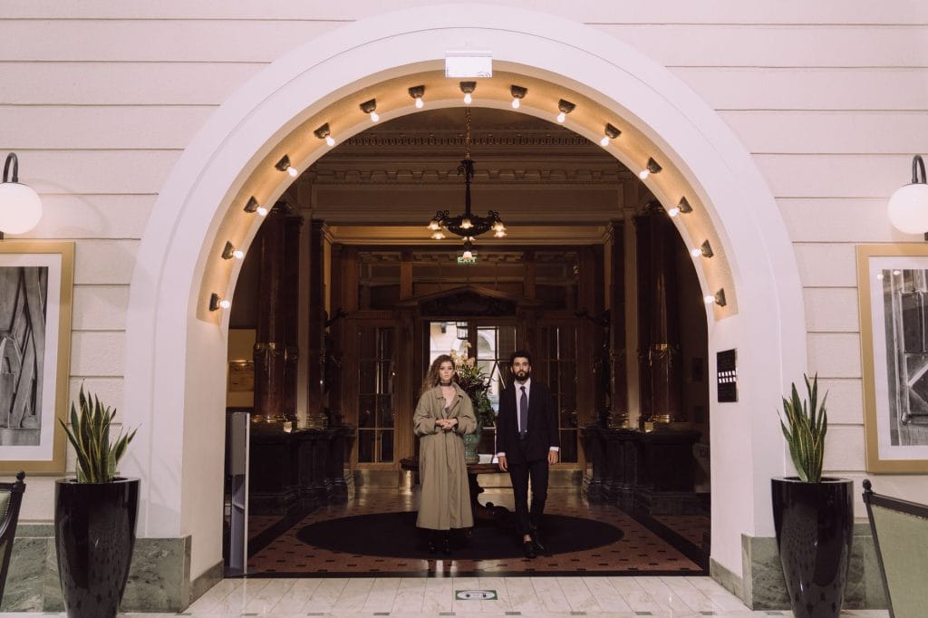 Para przed eleganckim wejściem do hotelu pod oświetlonym łukiem